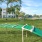 a large green field with a trampoline and a building in the background