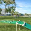 a large green field with a trampoline and a building in the background